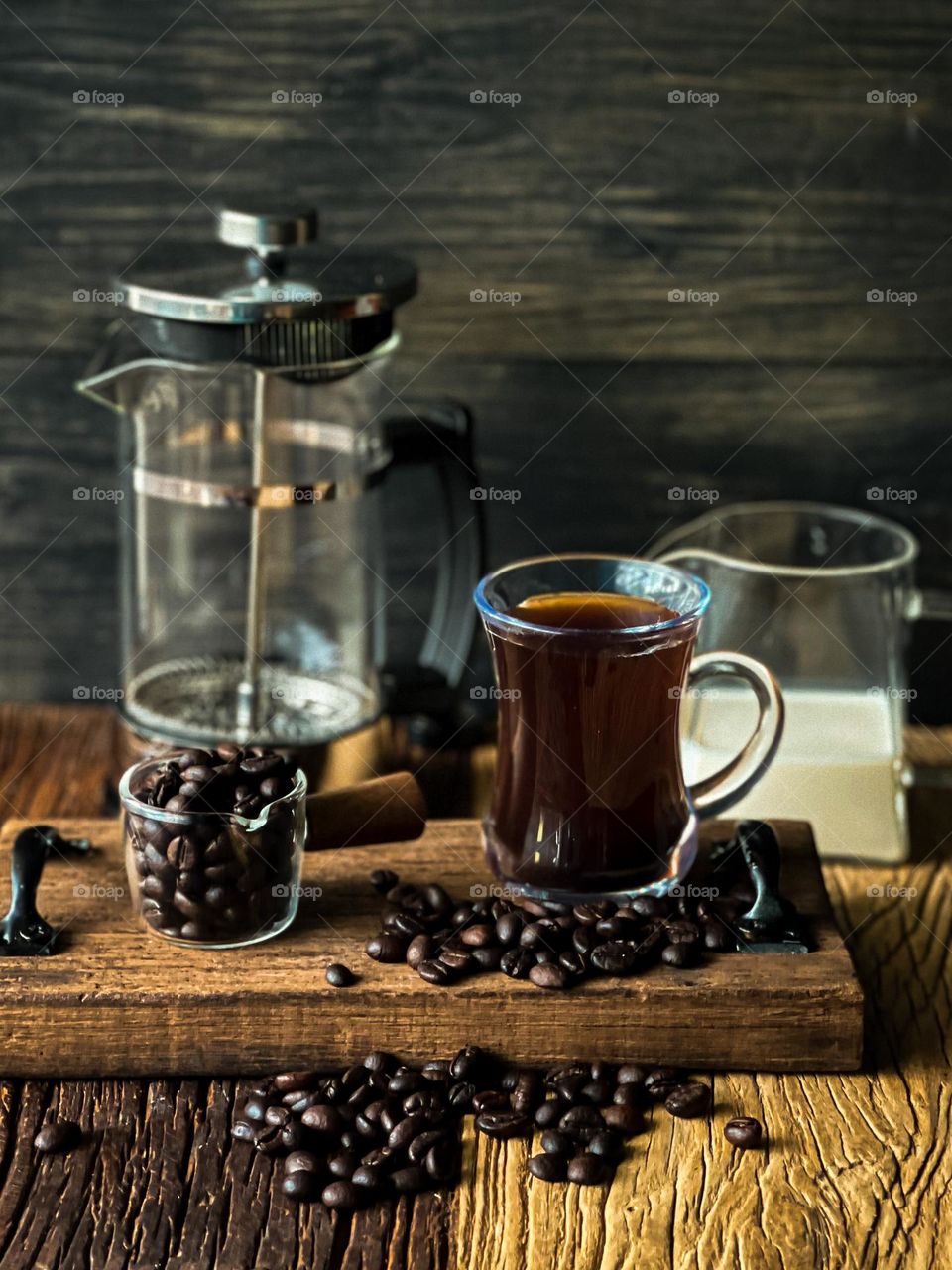 Coffee beans and a cup of black hot coffee with coffee preparation tools at the background 