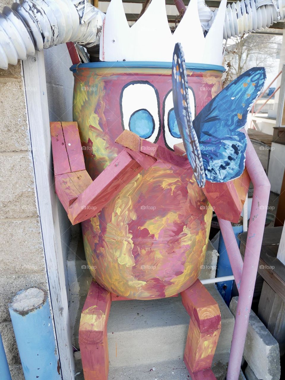 A tin can moose holding a butterfly, outside of a plant exchange.