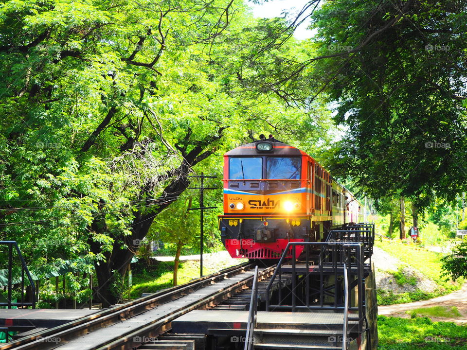 train coming to terminal,railway with tree,sunlight,blue sky background landscape,railway in thailand with old train