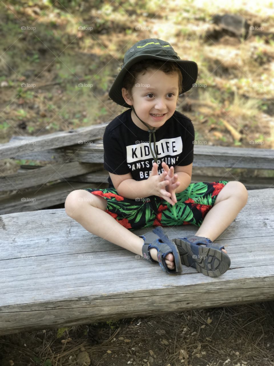 An adorable little boy wearing a hat out hiking in the woods of Central Oregon on a sunny summer day. 