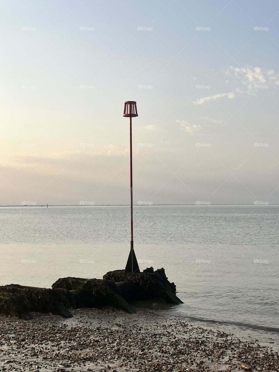 Warm summer evenings, strolling along the beach when most people have gone home. A beacon upon rocks silhouetted in the evening sunshine. Peaceful and calm all around.