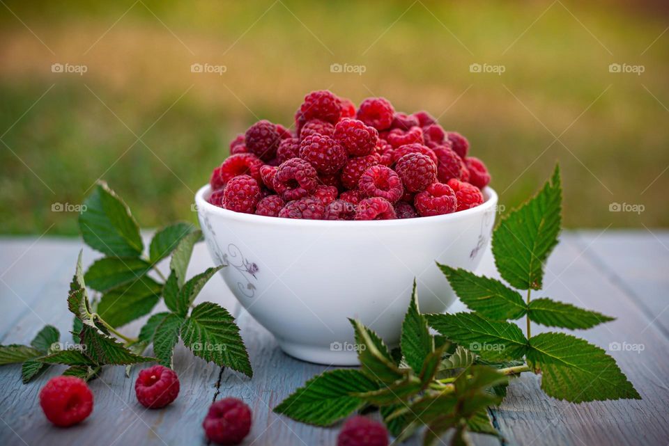 fresh harvest of ripe raspberries in a cup on the street