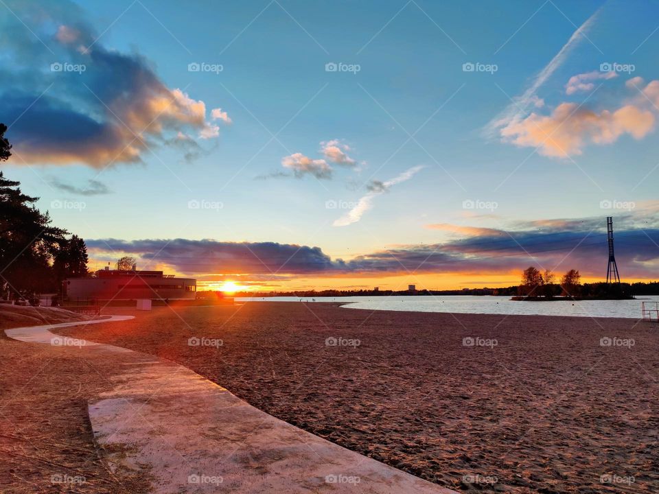 Beautiful sunset landscape on the Gulf of Finland from the sandy beach shore with concrete footpath