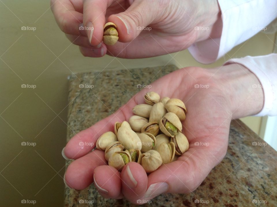 Holding a handful of pistachio nuts.