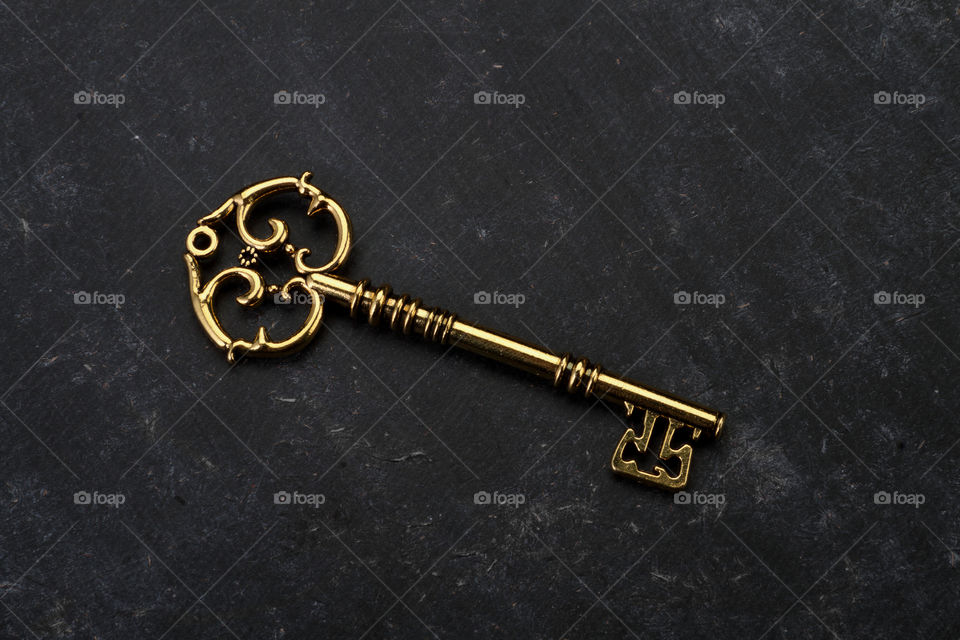 Beautiful golden vintage key on black background