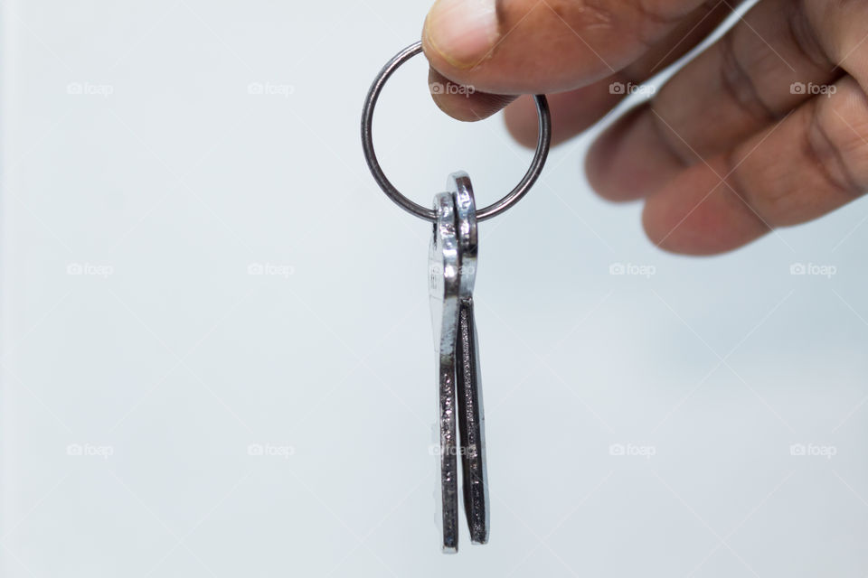 Male hand holding keyring isolated on white background with copy space area. Car key and block key isolated over white background with keyring.