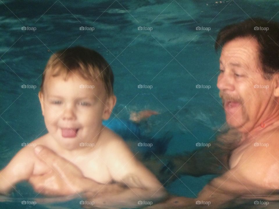 Grandfather and grandson swimming in pool
