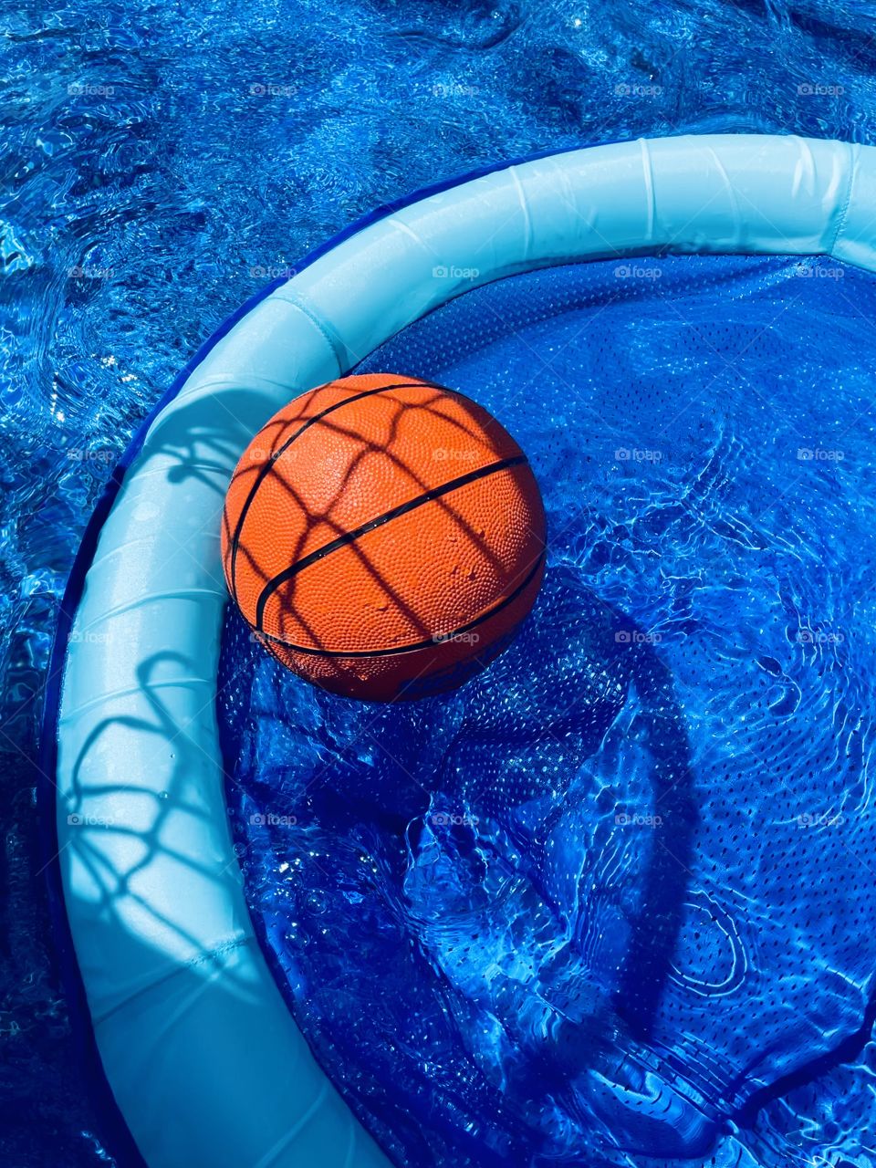 Shadows of a basketball net on by pool