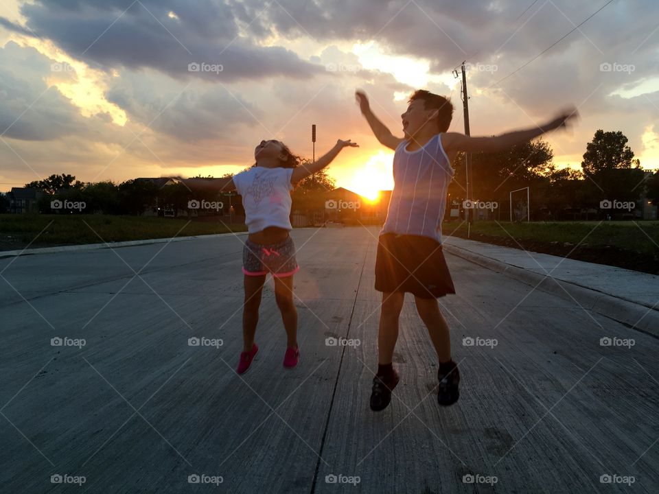 children jumping, playing and having fun during the sunset