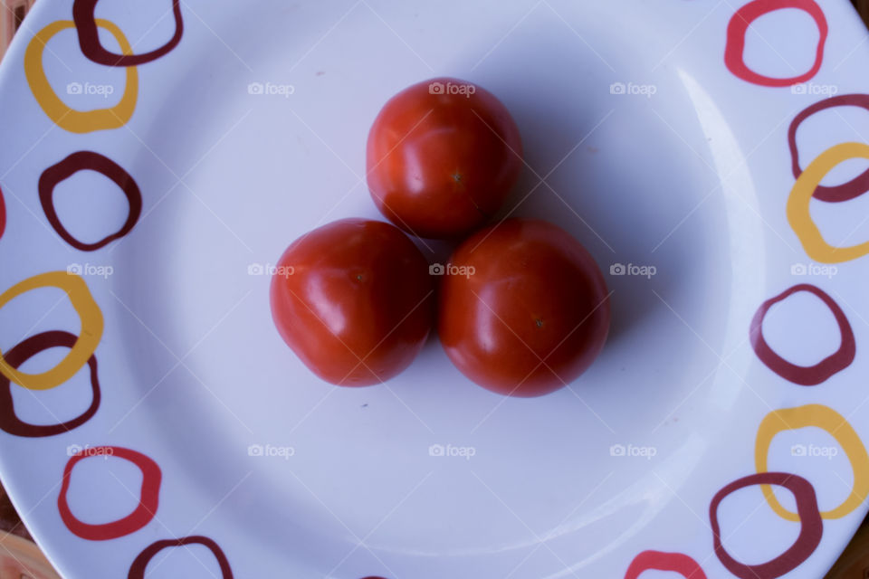 three red tomatoes on a plate