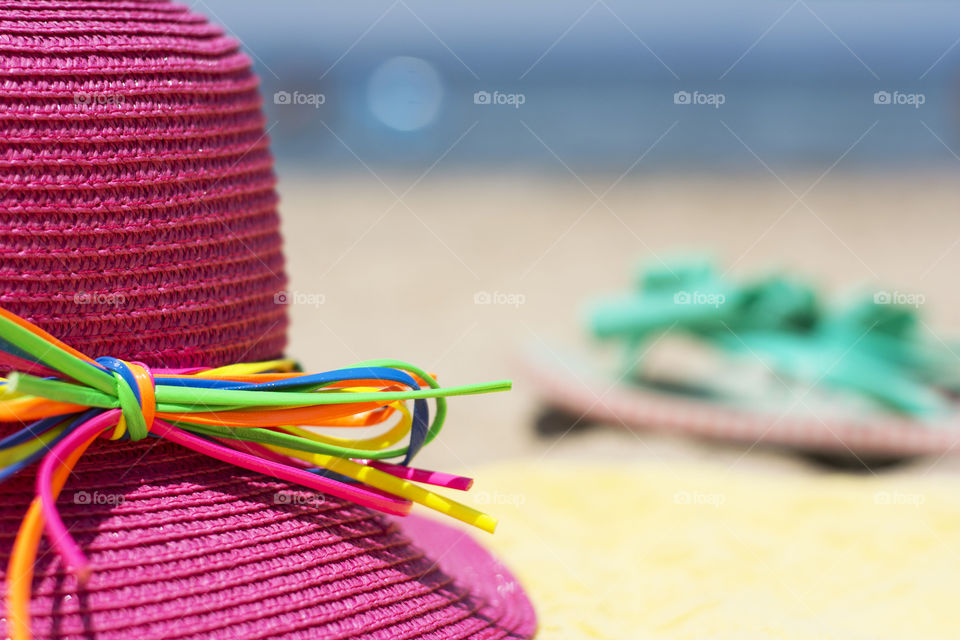 pink summer hat. pink summer hat with colorful bow tied on a sandy beach
