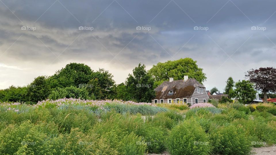 A danish house in foreground with a storm in background