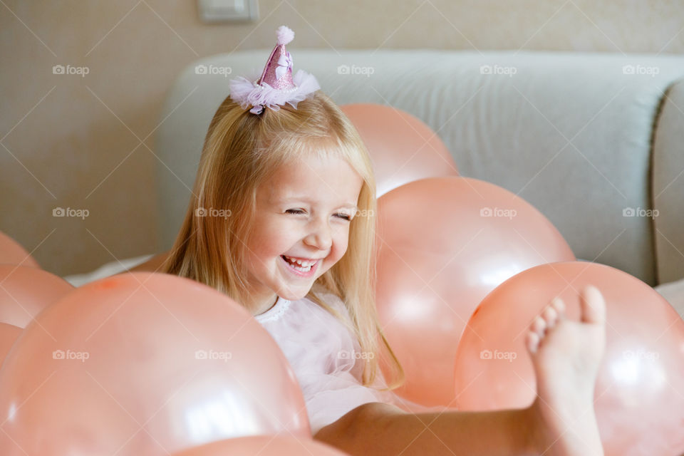 Happy little girl with blonde hair and birthday balloons 