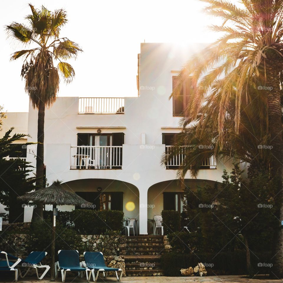 sun rises over holiday hotel with sun loungers at the front