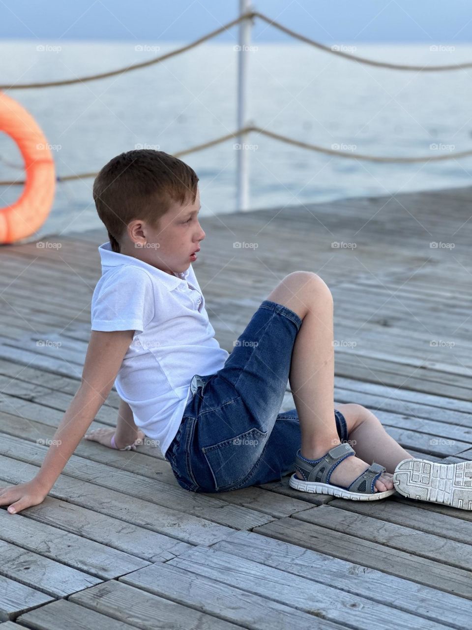 Boy resting meditation on the pier by the sea