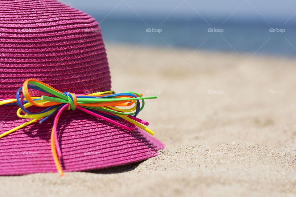 pink hat on beach. pink hat with colorful bow tied on a beach