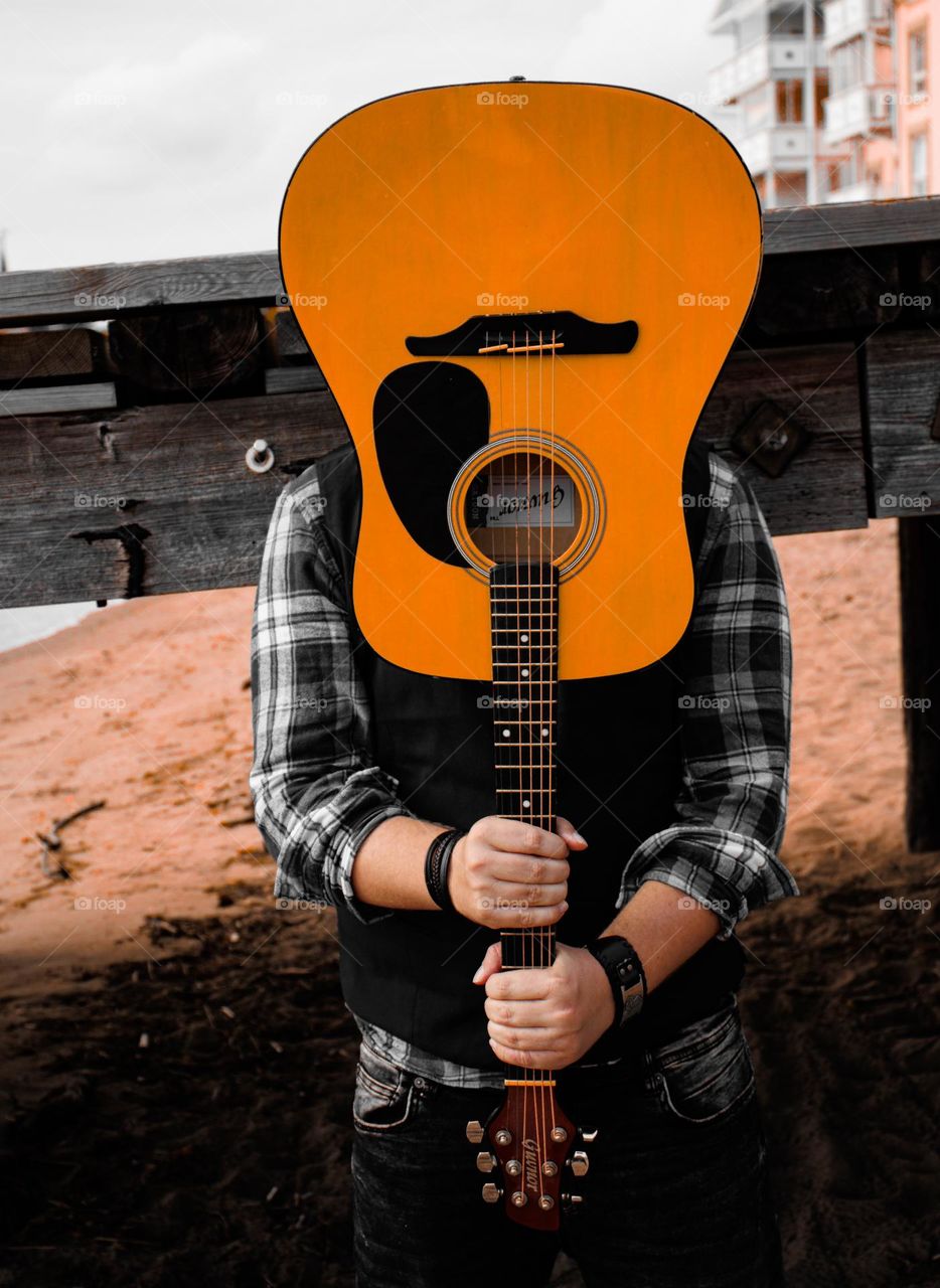 A Man with his guitar . A portrait of a man with his guitar at the beach