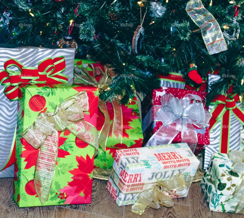 Pretty colorfully wrapped gifts under a green Christmas tree. 