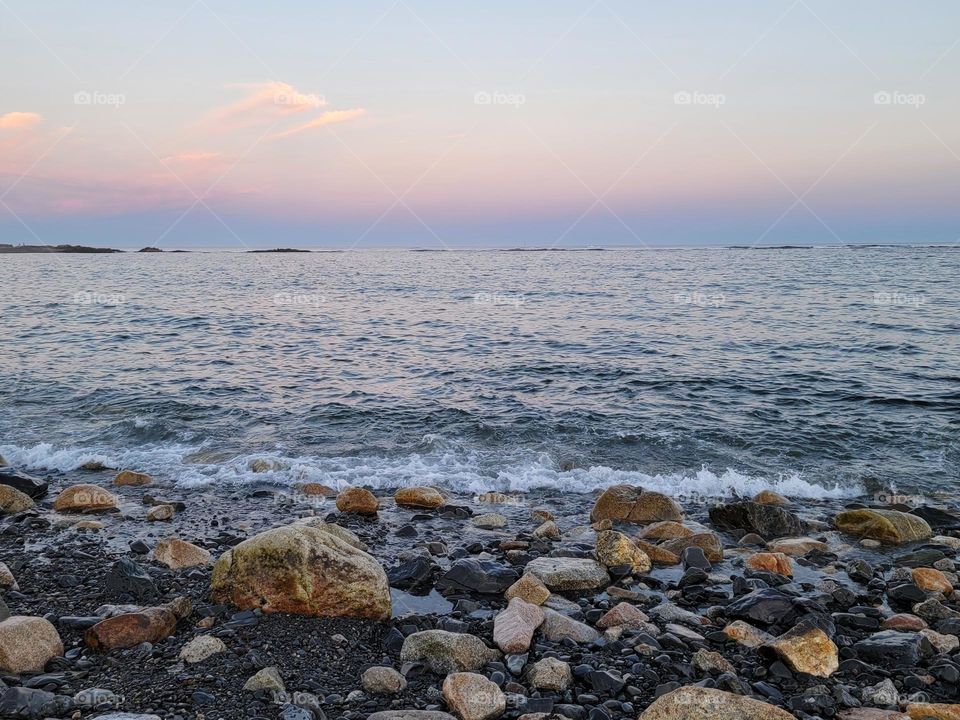 Rocky Shoreline Covered with Pink Cotton Candy Sky in the Background at Dusk