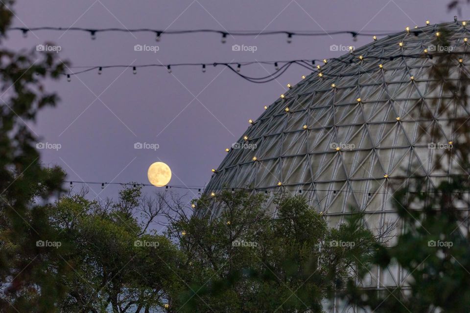 Cinesphere dome in Ontario Place with lights on it as the full moon rises in the background