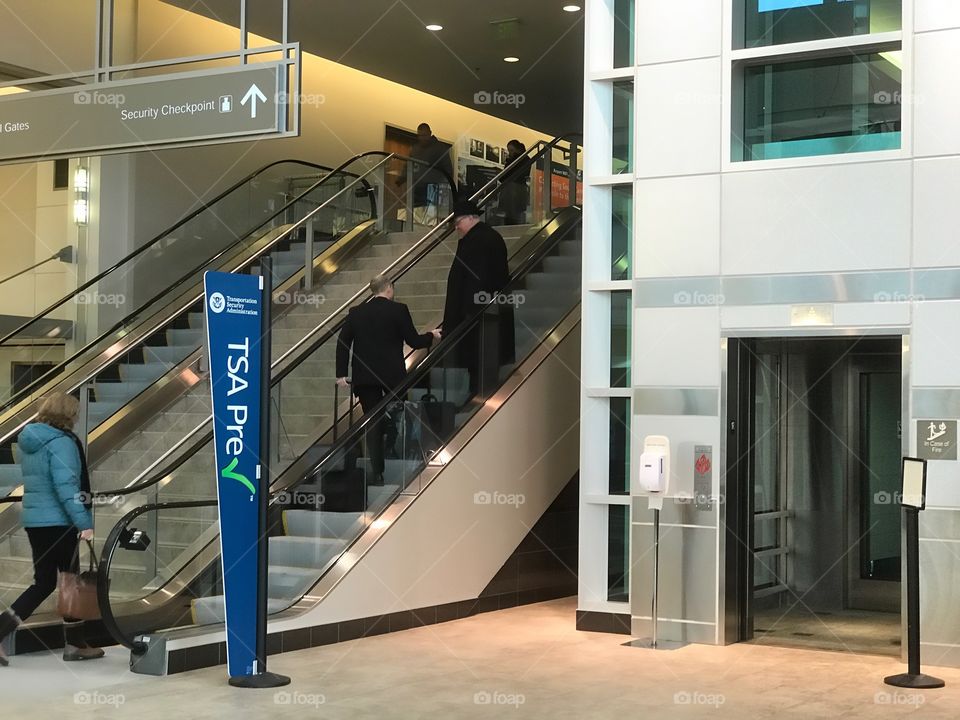 Business travelers at the airport. Escalators moving people up and down. 