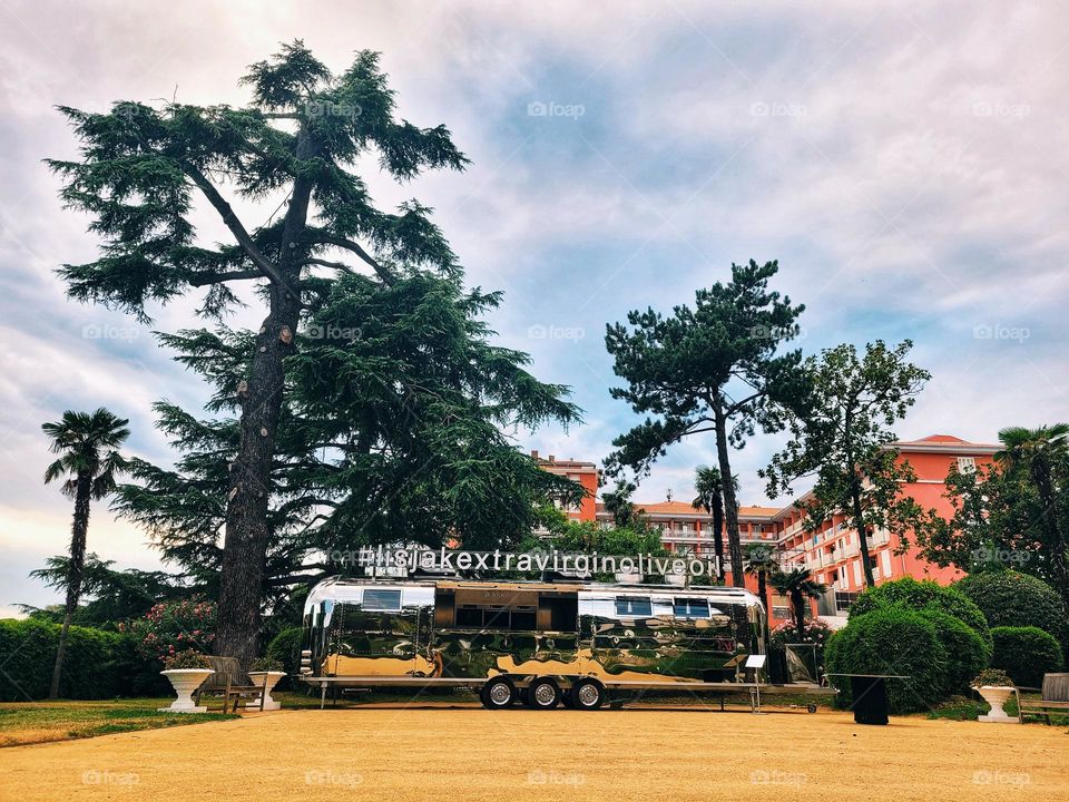 Urban city view of green pine trees in park at Adriatic seaside and hippie bus.