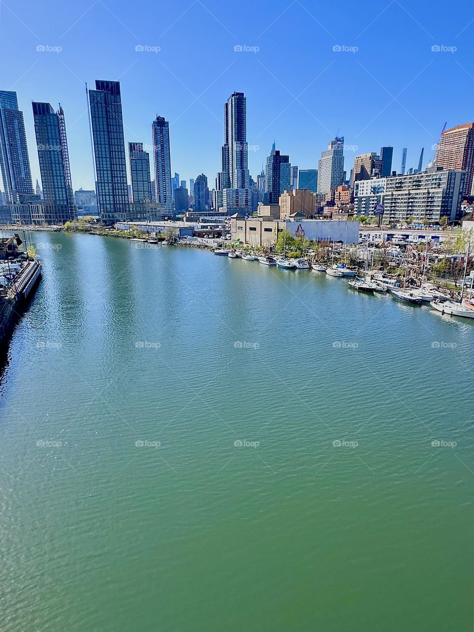 This is picturesque “Newtown Creek” with its great variety of boats seen from the “Pulaski Bridge” that connects “Greenpoint”, Brooklyn to LIC, Queens. Across the “East River” in the distance we see “Manhattan”. 2024. Hypnotic Productions
