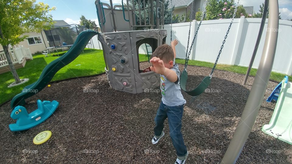 young boy jumping from a swing