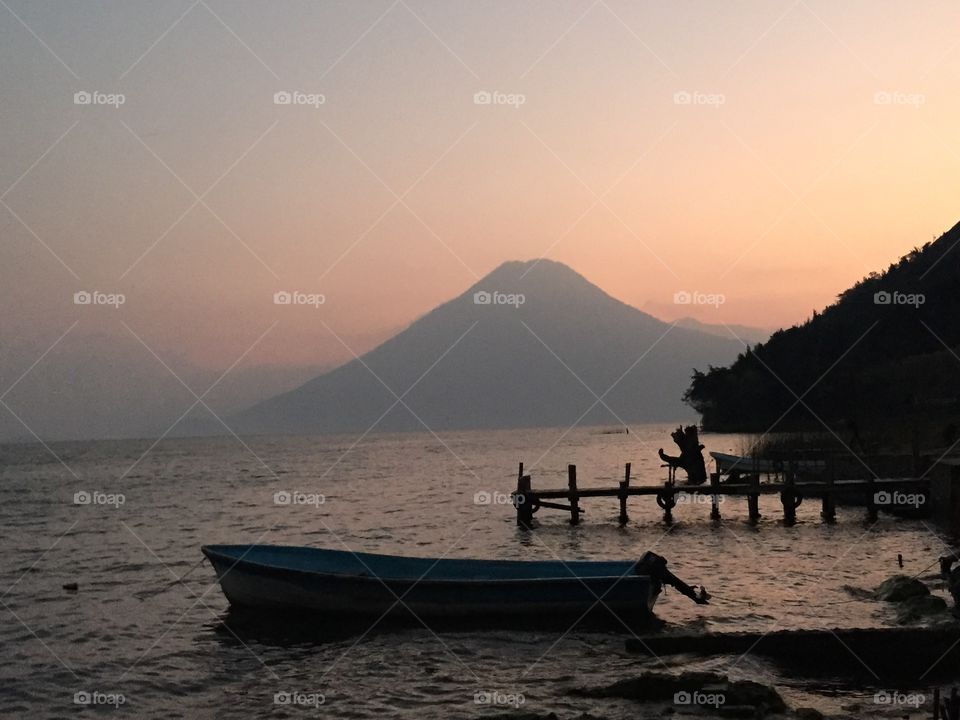 Sunrise over Lake Atitlan. Boats and docks on Lake Atitlan at misty sunrise, volcano in background 