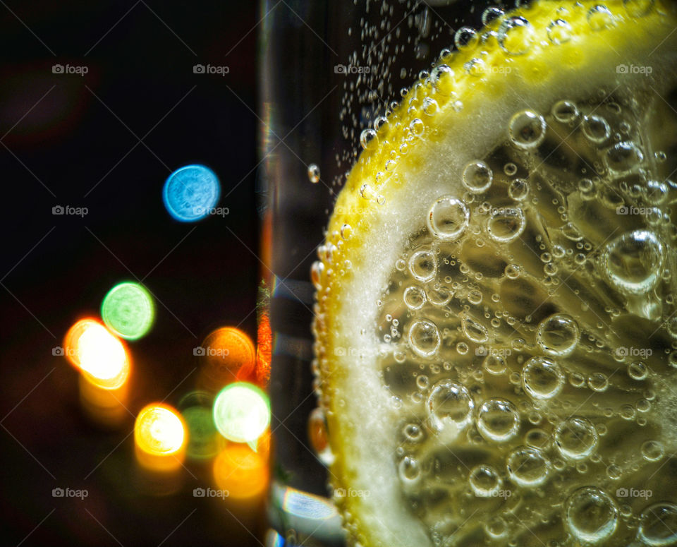 Lemon in a glass of soda on the background of lights