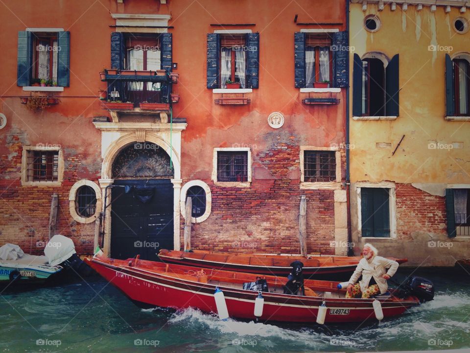 Famous colorful architecture of Venice in Italy. I was lucky to catch a moment of this happy smiling man enjoying his gondola ride with his best friend. :)