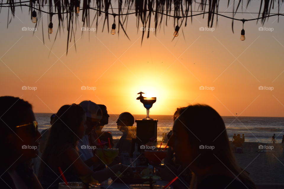 Silhouette of a margarita durning a beach sunset. People enjoying the nice weather and a good beverage. 