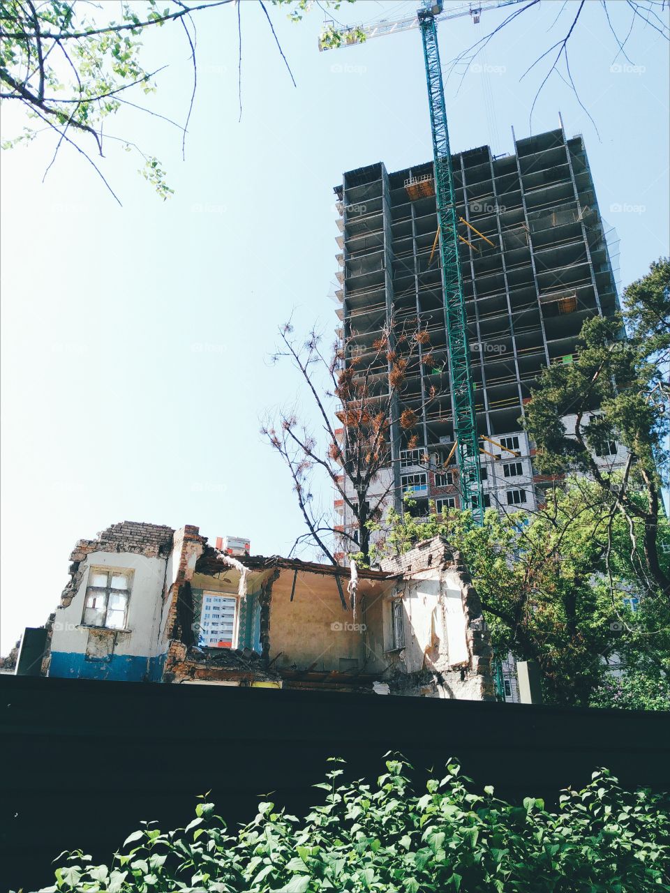 Old destroyed house on the background of building a new apartment house