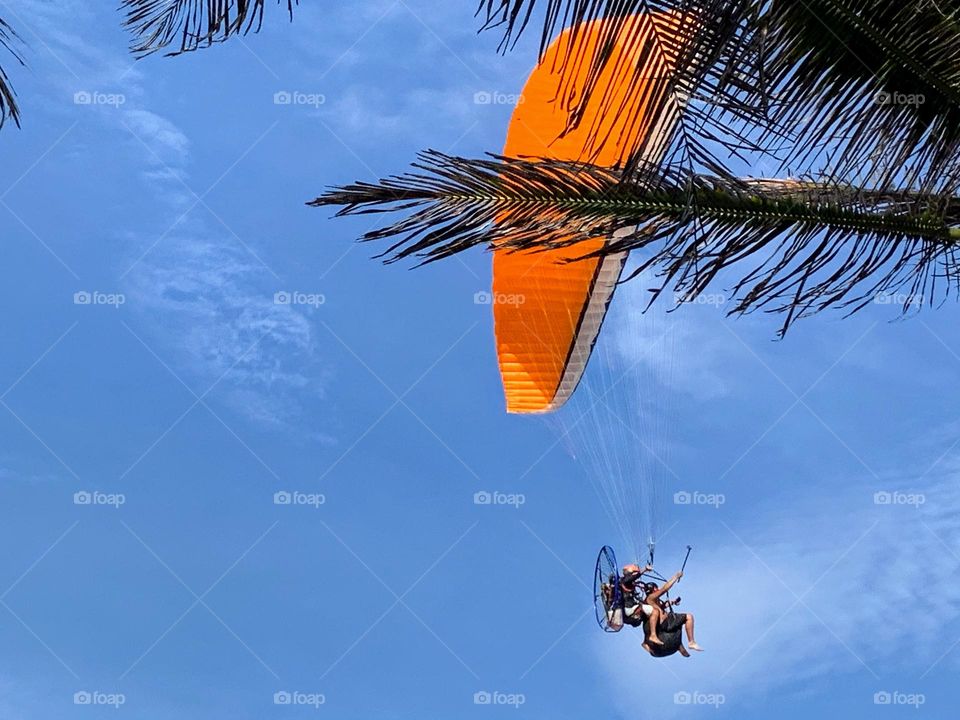 Orange paraglider on blue sky 