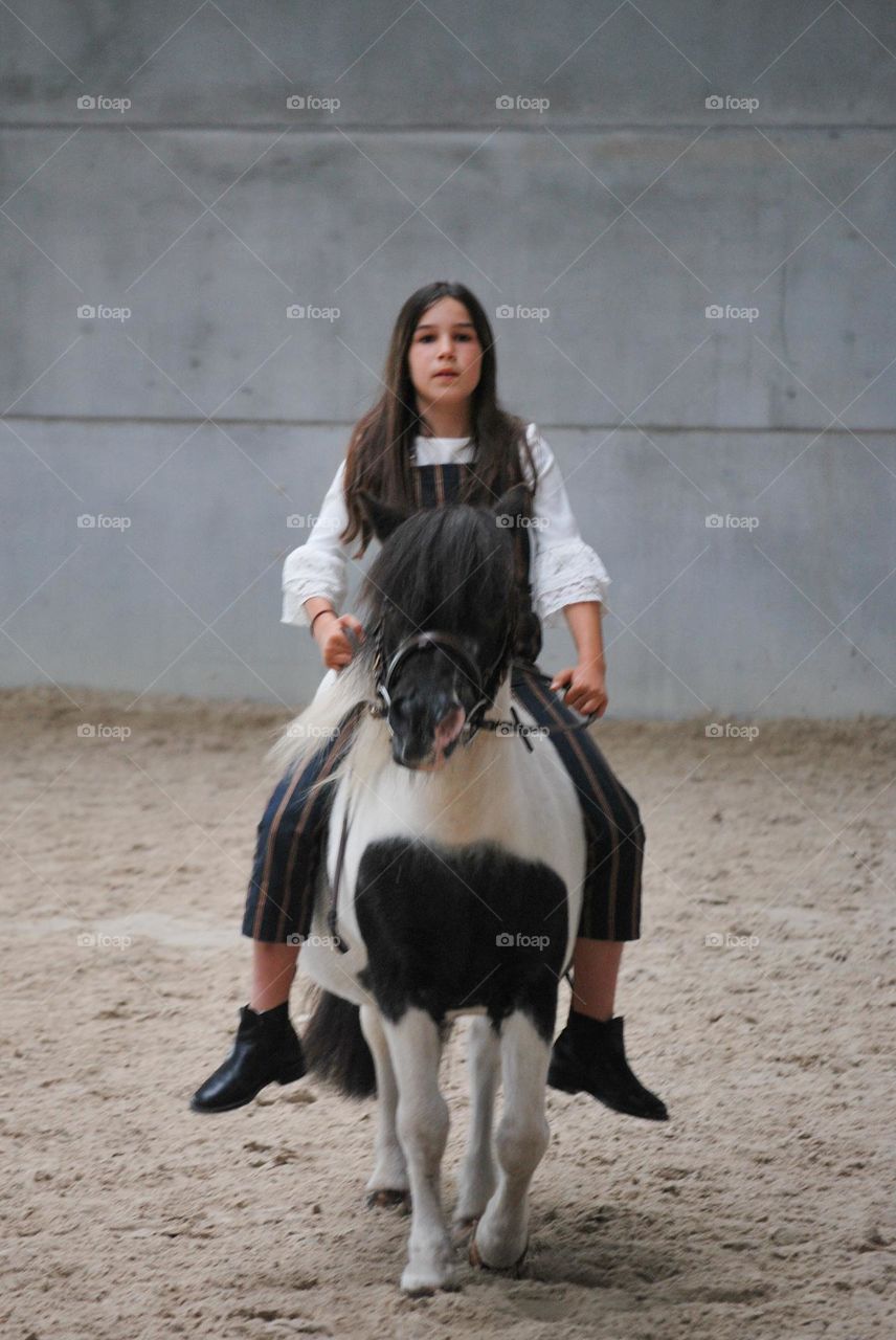 Teenage girl riding her horse in a stable