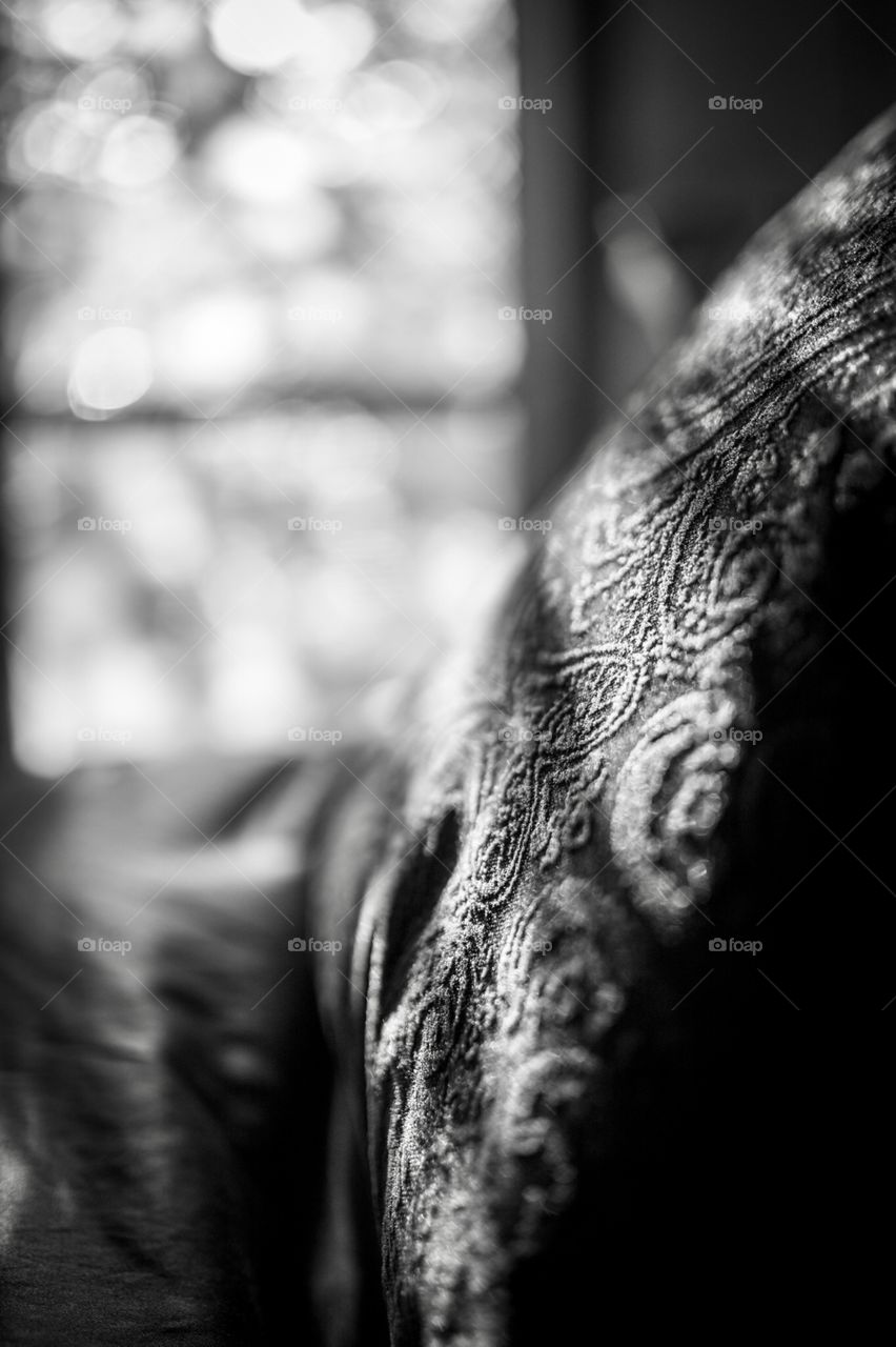 Dappled lighting coming in through the window onto a cozy bed. 