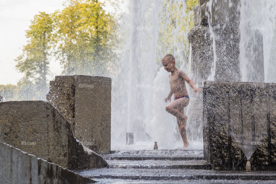 a boy playing in fountain