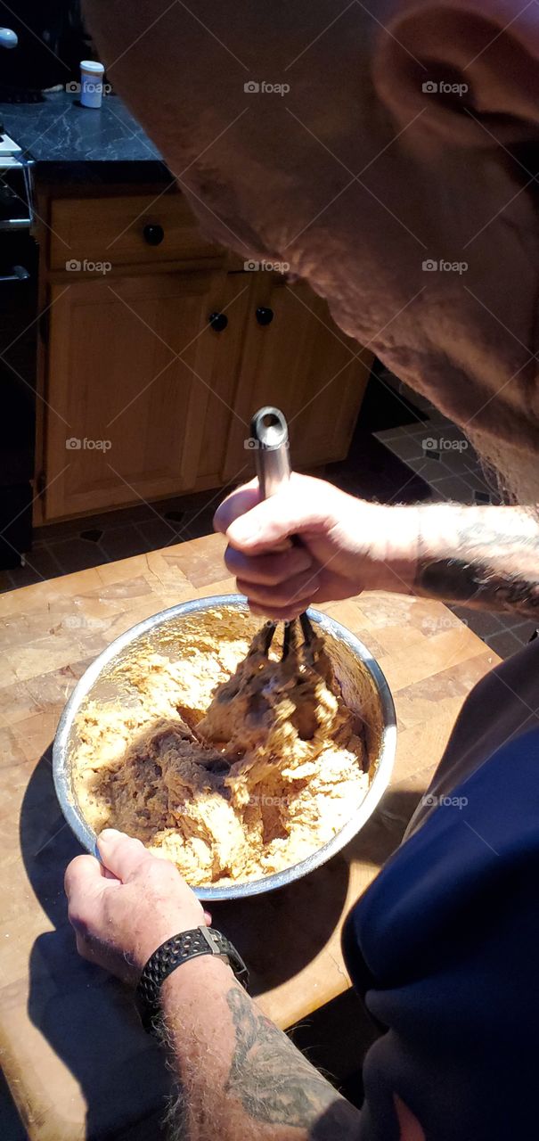View of man wisking ingredients for sweet potato muffins. He'll pour into muffin pans & bake. Makes a dozen muffins.