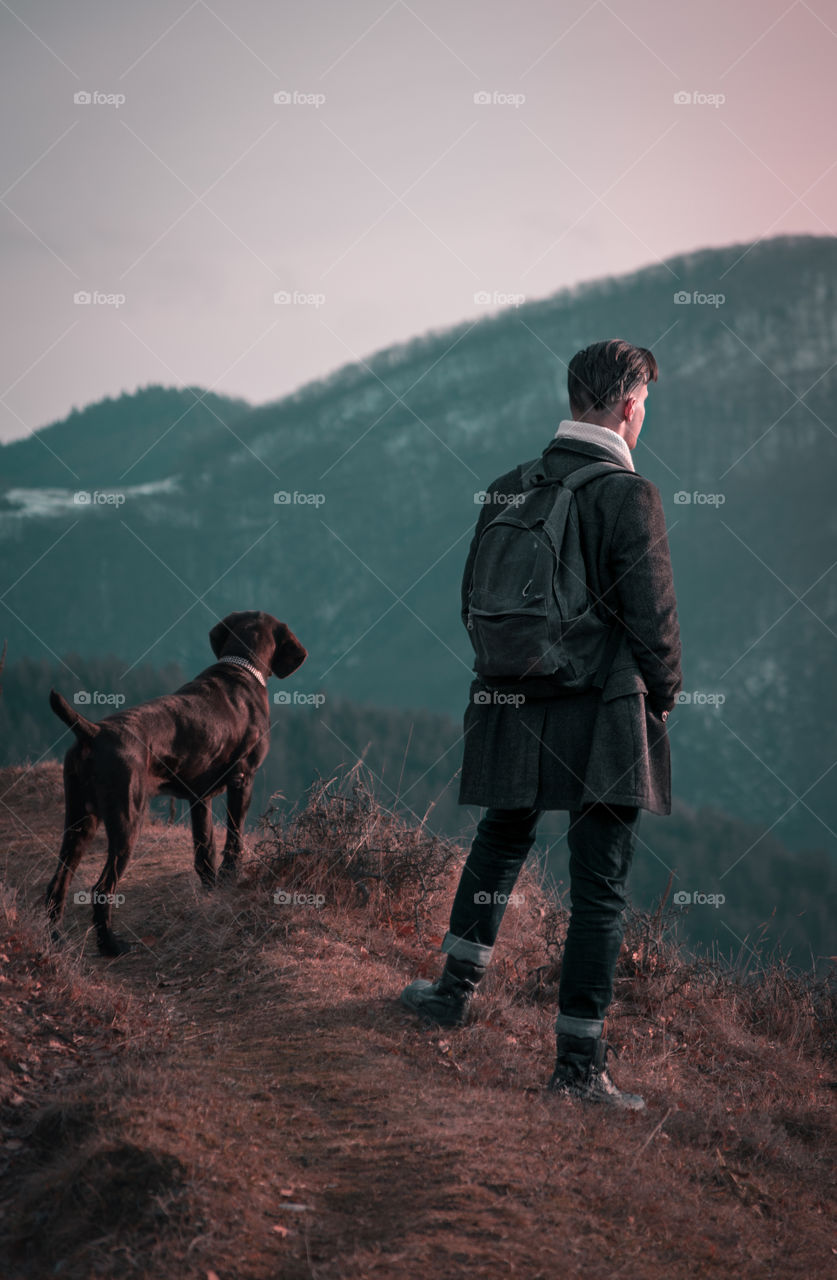 Man with a dog in the mountains.