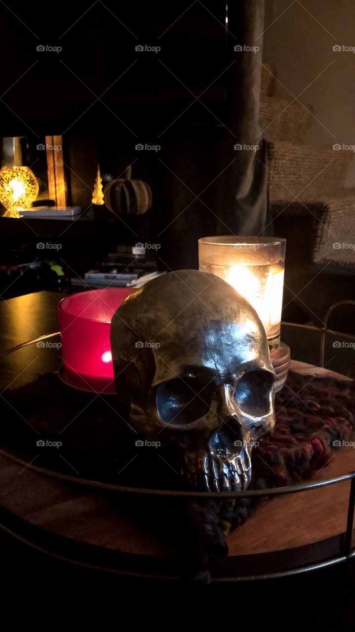 Spooky skeleton skull and candles on a cozy living room. 