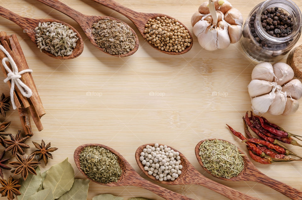 Different spices on wooden spoons on top of a chop board 