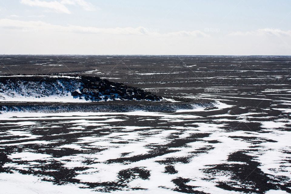 Over view of snow and black sand