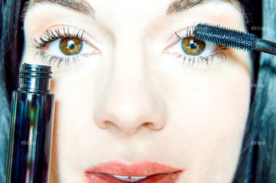 Close-up of a young woman's face and mascara wand