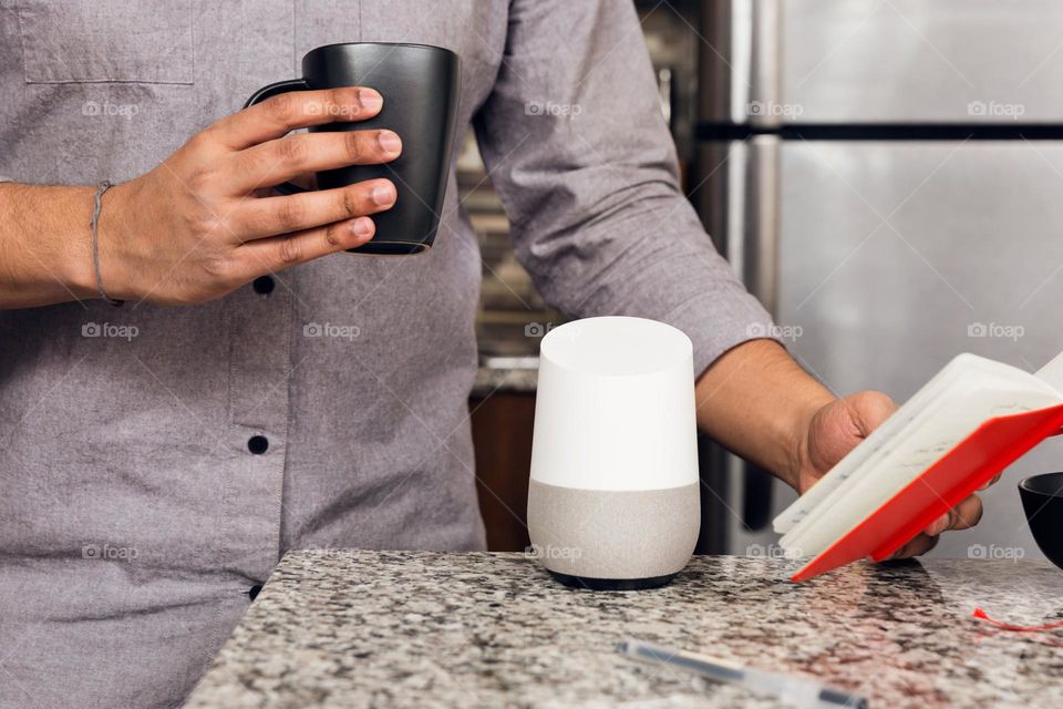 With a cup of coffee  and a smart home assistant by his side, this man looks through his to-do list and prepares for the day.
