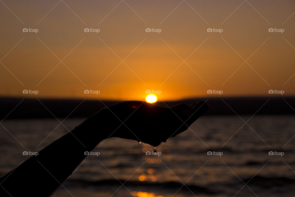 Silhouette of human hand in front of beach