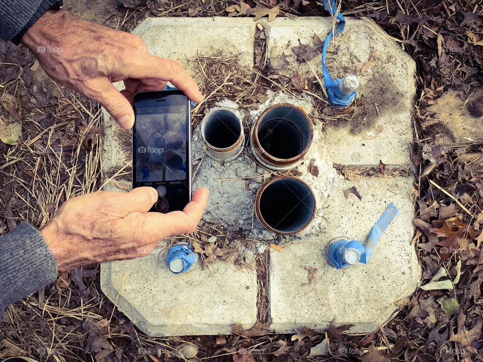 A person taking a photo of lamp post anchor 