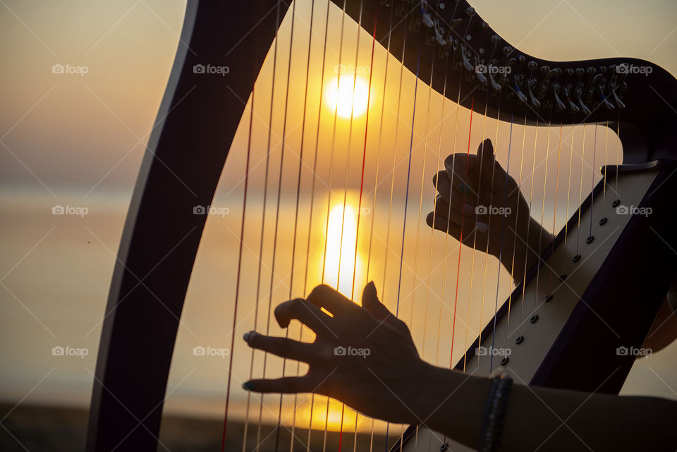 Closeup of hands playing celtic harp during sunset