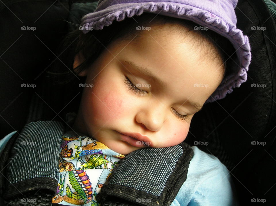 A closeup of the rosy-cheeked sleeping face of my daughter. She is in in her car seat and fell asleep on the way home from a long playdate with mom at the beach. The sun was shining on her face and she looked so beautiful, peaceful and angelic.