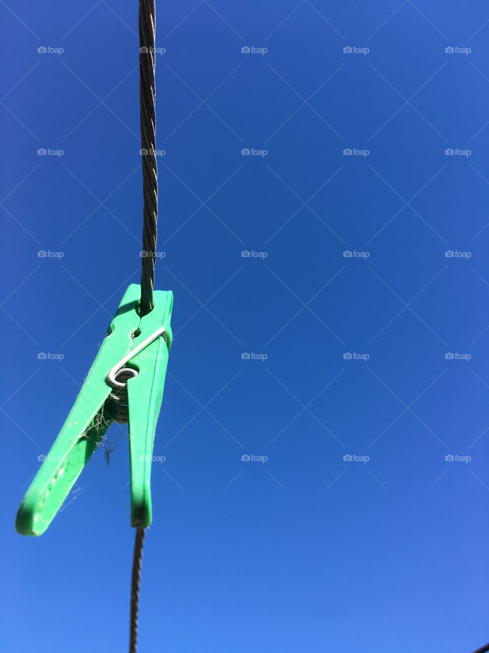 Bright green clothes peg against vivid indigo sky