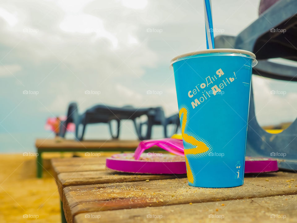 Bright cup with a cocktail on a sunny beach